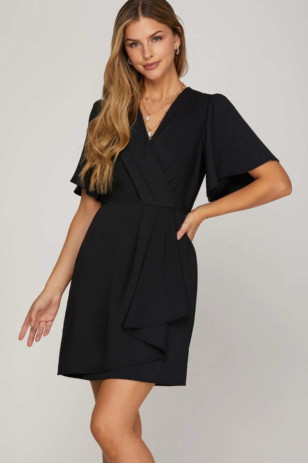 Elegant ruffled surplice mini dress with flutter sleeves, styled for a feminine summer look.