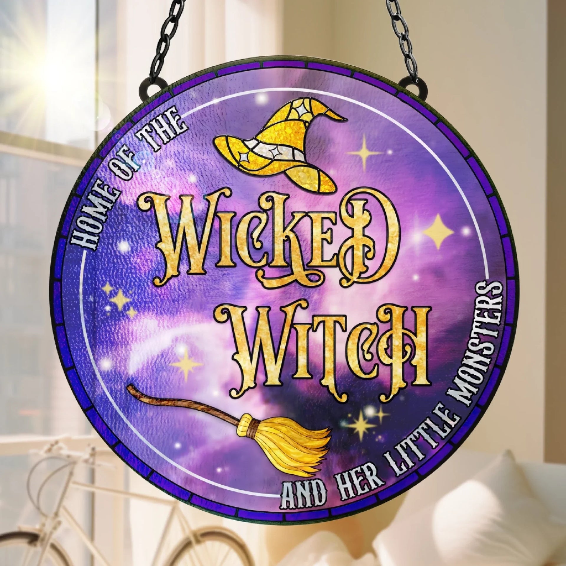 Round acrylic suncatcher featuring a Wicked Witch theme with purple background, yellow witch hat, and broomstick hanging in a window.