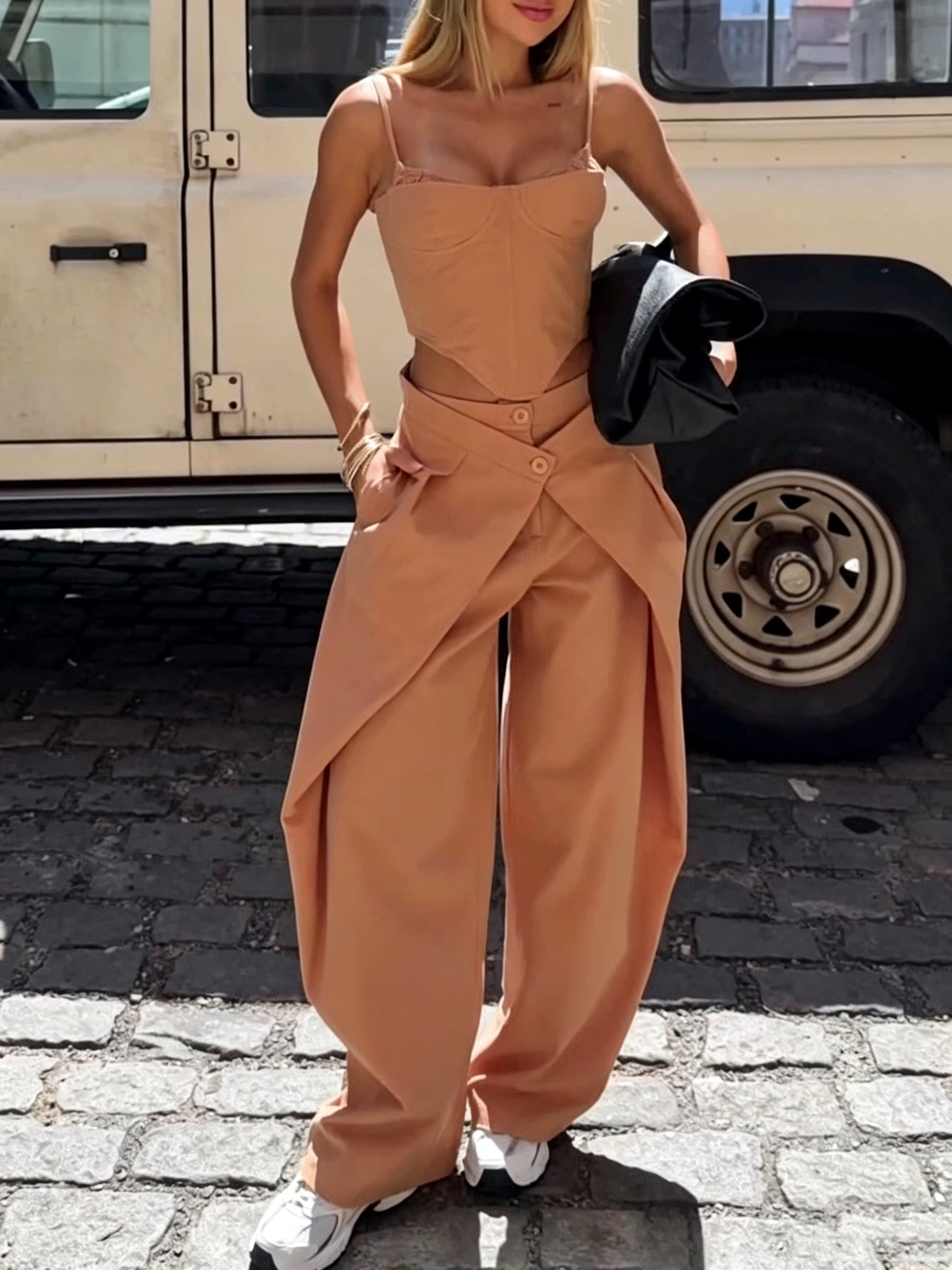 A woman wearing a camel-colored two-piece set with a spaghetti strap corset top and wide-leg wrap-waist pants.