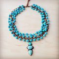 Triple strand turquoise bead necklace with a copper-tone chain and three-stone droplet pendant.