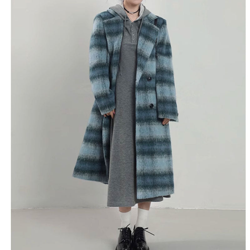 Woman wearing a Japanese style blue plaid double-breasted woolen overcoat with a relaxed fit, layered over a grey dress