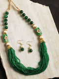 Gold-polished traditional jewelry set featuring green beads and pearl accents