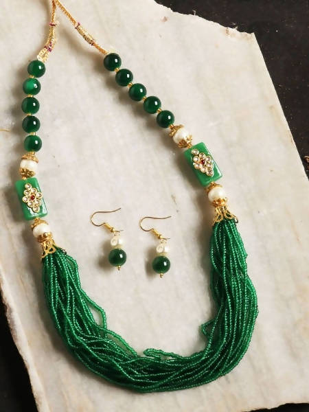 Gold-polished traditional jewelry set featuring green beads and pearl accents