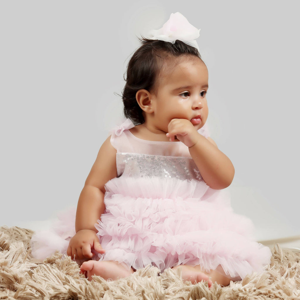 Girl wearing a pink and grey sequin gown with frill hem and floral shoulder detail