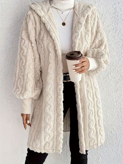 Woman wearing a cozy long beige fuzzy hooded jacket with an open-front design.