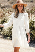 Front and back view of the white Whitley Floral Lace Patchwork Tiered Mini Dress on a model outdoors.