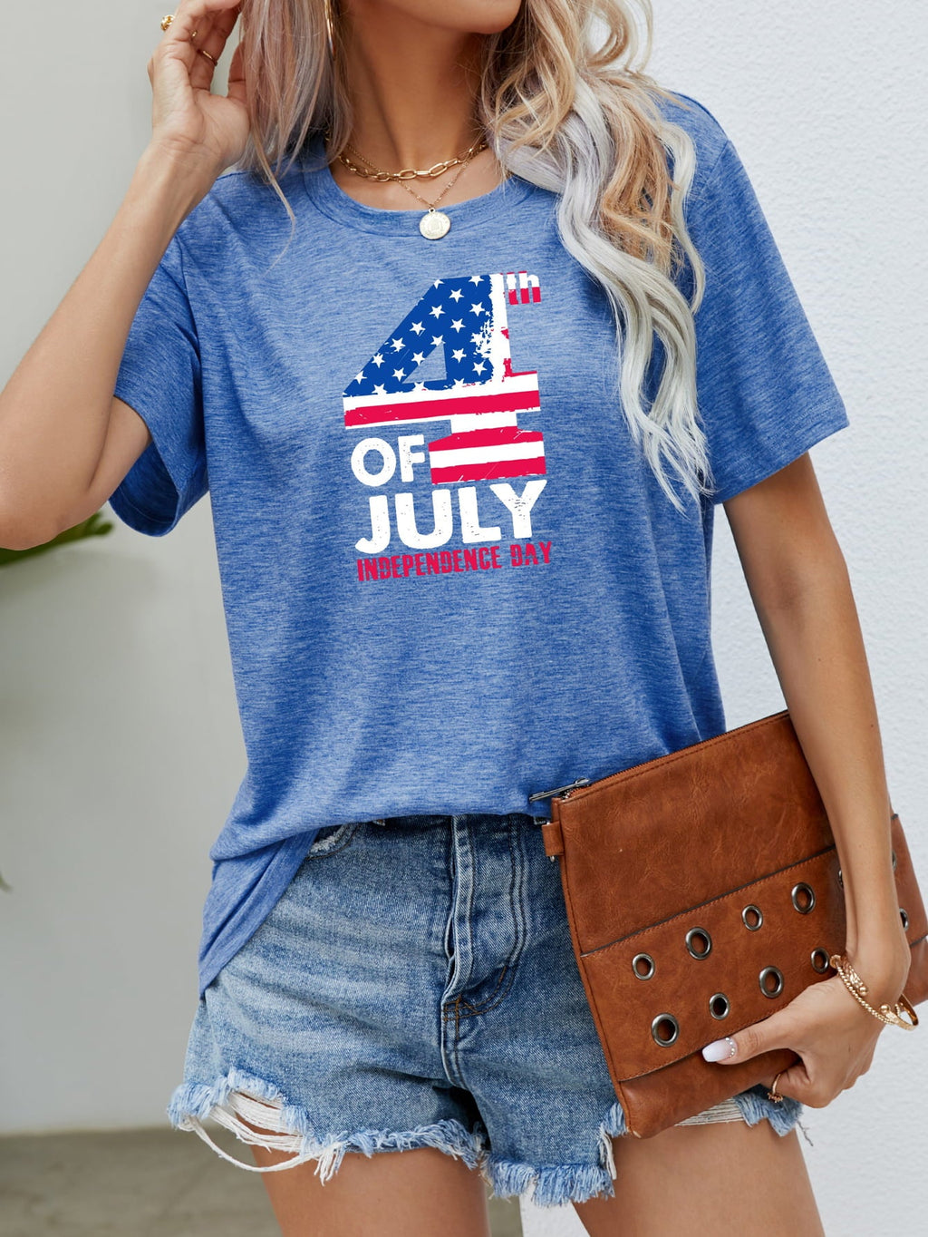 A woman wearing a blue short-sleeved t-shirt with a 4th of July Independence Day flag graphic print.