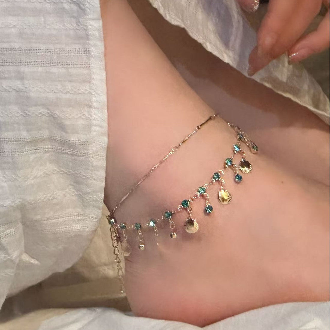 Double-layer shell anklet featuring shimmering rhinestones and tassel details on a display card.