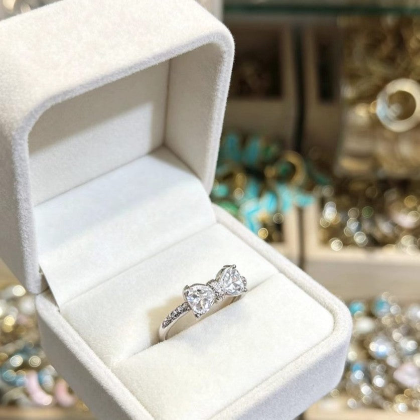 Close up of a polished silver bowknot ring worn on a woman's finger, romantic feminine style