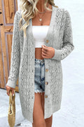 Model wearing a grey long sleeve openwork button down cardigan over a white tank top and denim shorts.