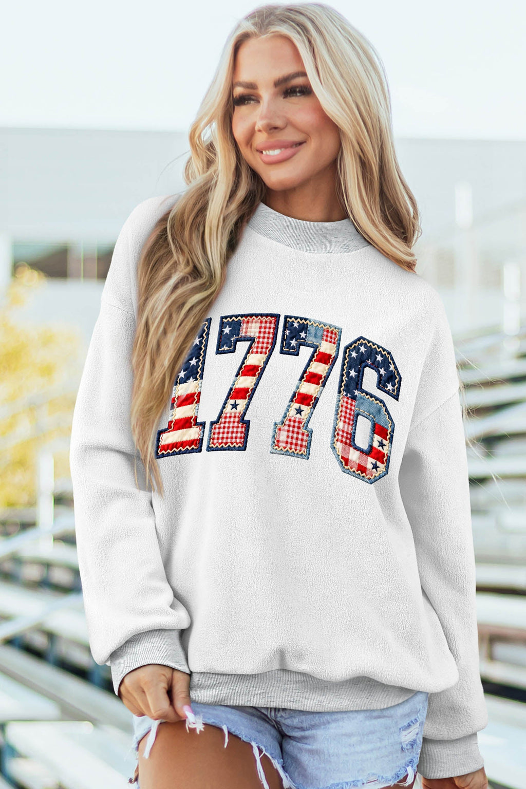 Woman wearing a white and grey Oakleigh print reversible mock sweatshirt with a flag pattern
