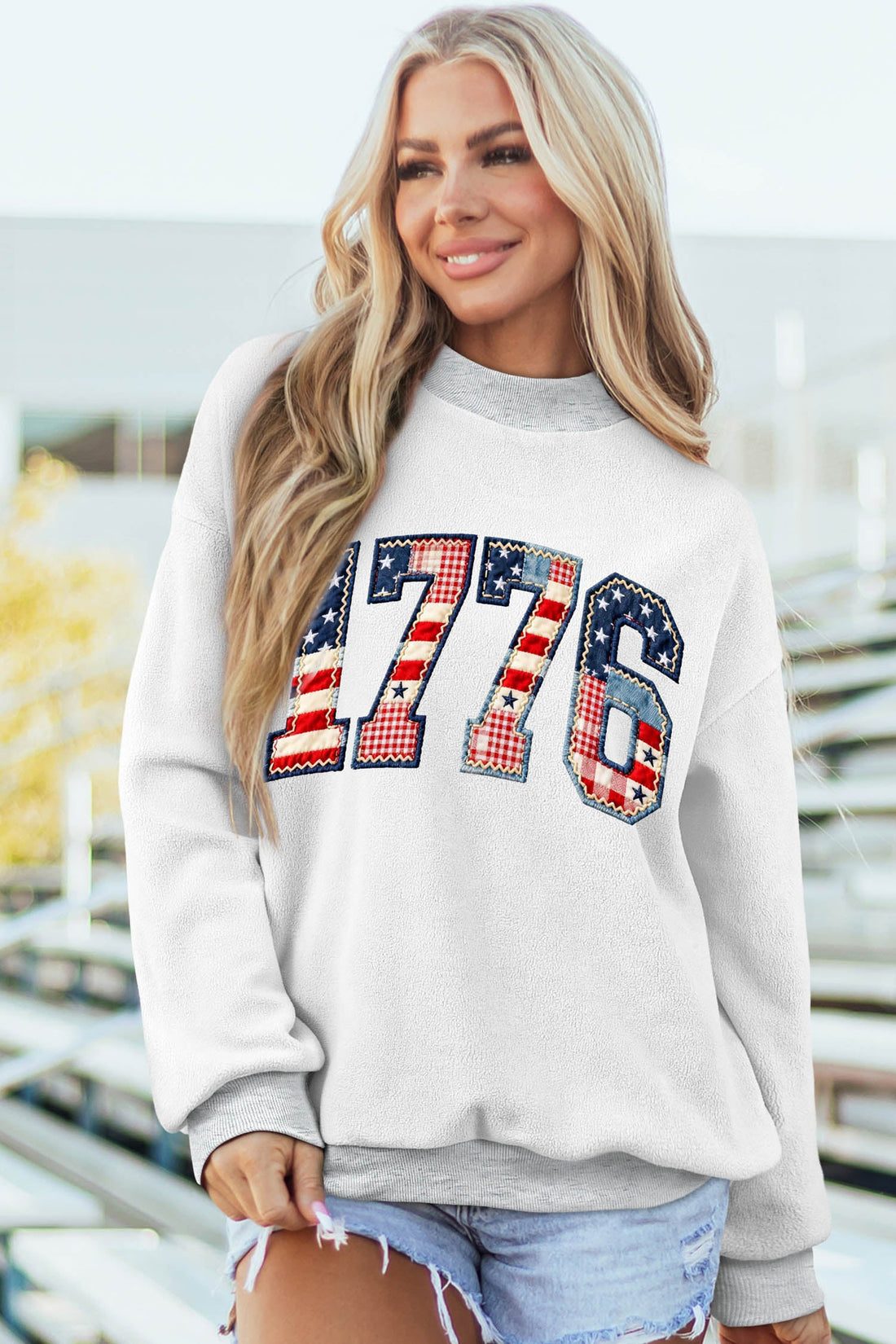 Woman wearing a white and grey Oakleigh print reversible mock sweatshirt with a flag pattern