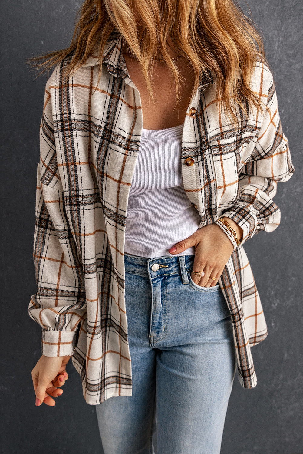 Woman wearing an oversized plaid shacket in off-white, brown, and black with side slits