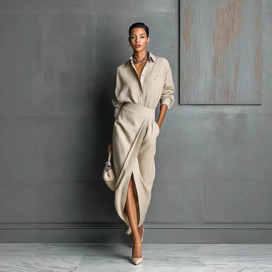 A woman wearing an elegant beige irregular pleated shirt dress with a button-front collar, styled with a matching handbag.