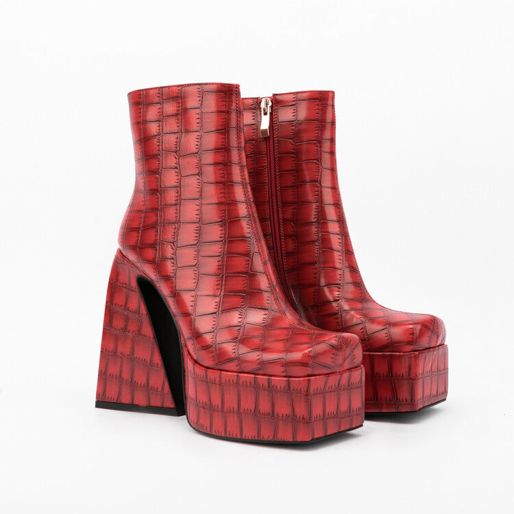 A pair of red crocodile-textured platform chunky heel ankle boots with a square toe on a white background, next to a pair of green snakeskin-textured platform chunky heel ankle boots.