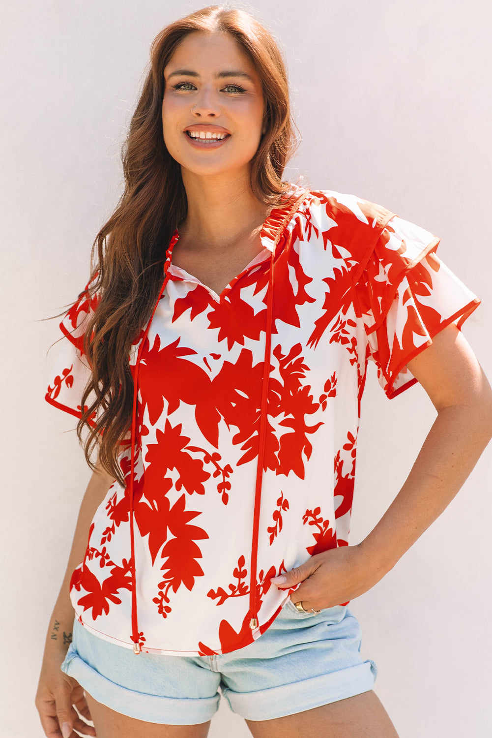 Woman wearing a red and white floral Zoya V-neck blouse with tiered ruffled sleeves