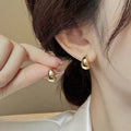Modern gold heart stud earrings on a minimalist background