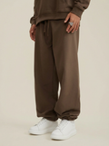 A pair of brown heavyweight 440 GSM cotton joggers with a loose, relaxed fit.