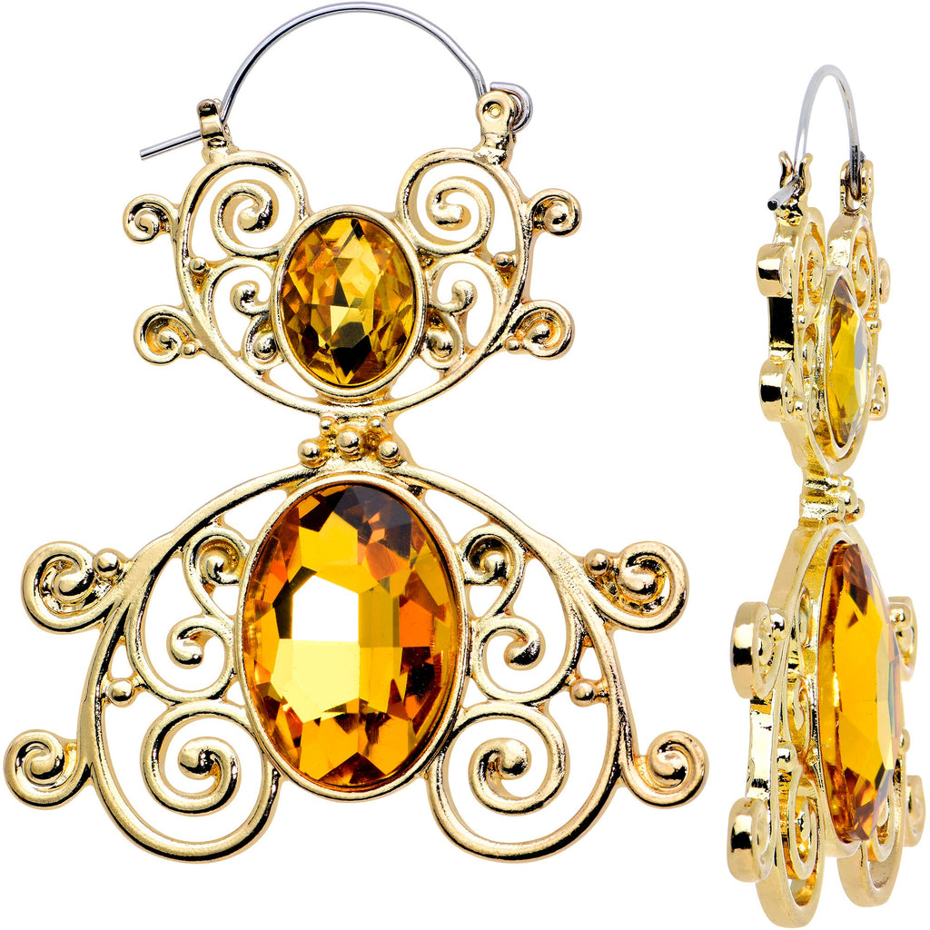 A pair of gold tone tunnel plug earrings featuring intricate scrolling metalwork and vibrant yellow oval gems, shown against a white background.