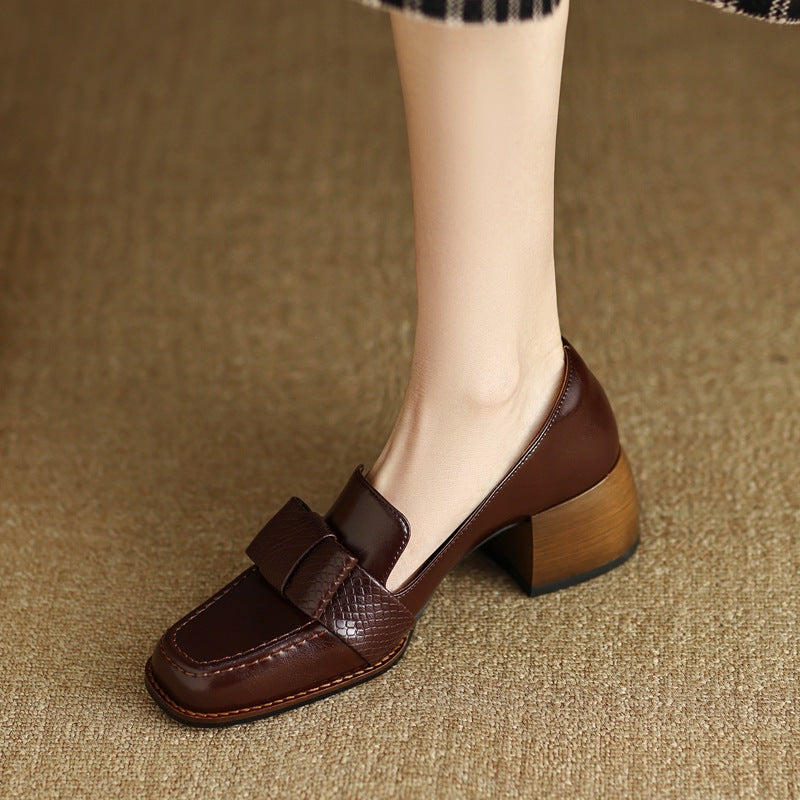 Close up of brown leather square toe pumps with a chunky block heel and bow detail.
