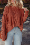 Close-up of a person wearing a burnt orange chunky cable knit sweater with a slouchy fit.