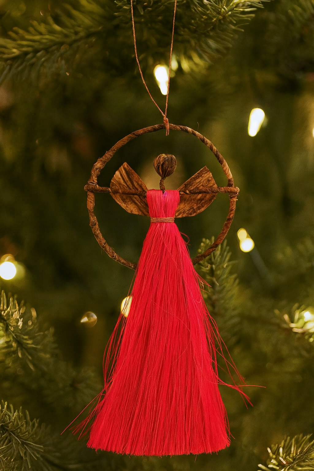 Handcrafted Ugandan banana fiber angel ornament in vibrant pink and blue colors with natural botanical accents.