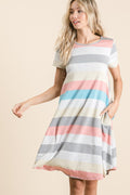 Woman wearing a casual short sleeve striped dress with functional side pockets.