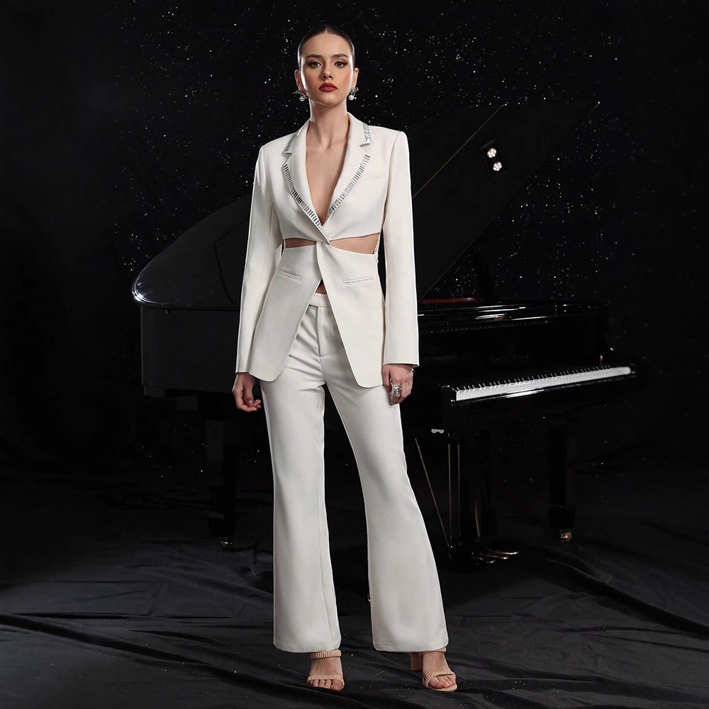 A woman wearing a crisp white suit set with a hollow-out blazer and wide-leg pants, standing in front of a grand piano.