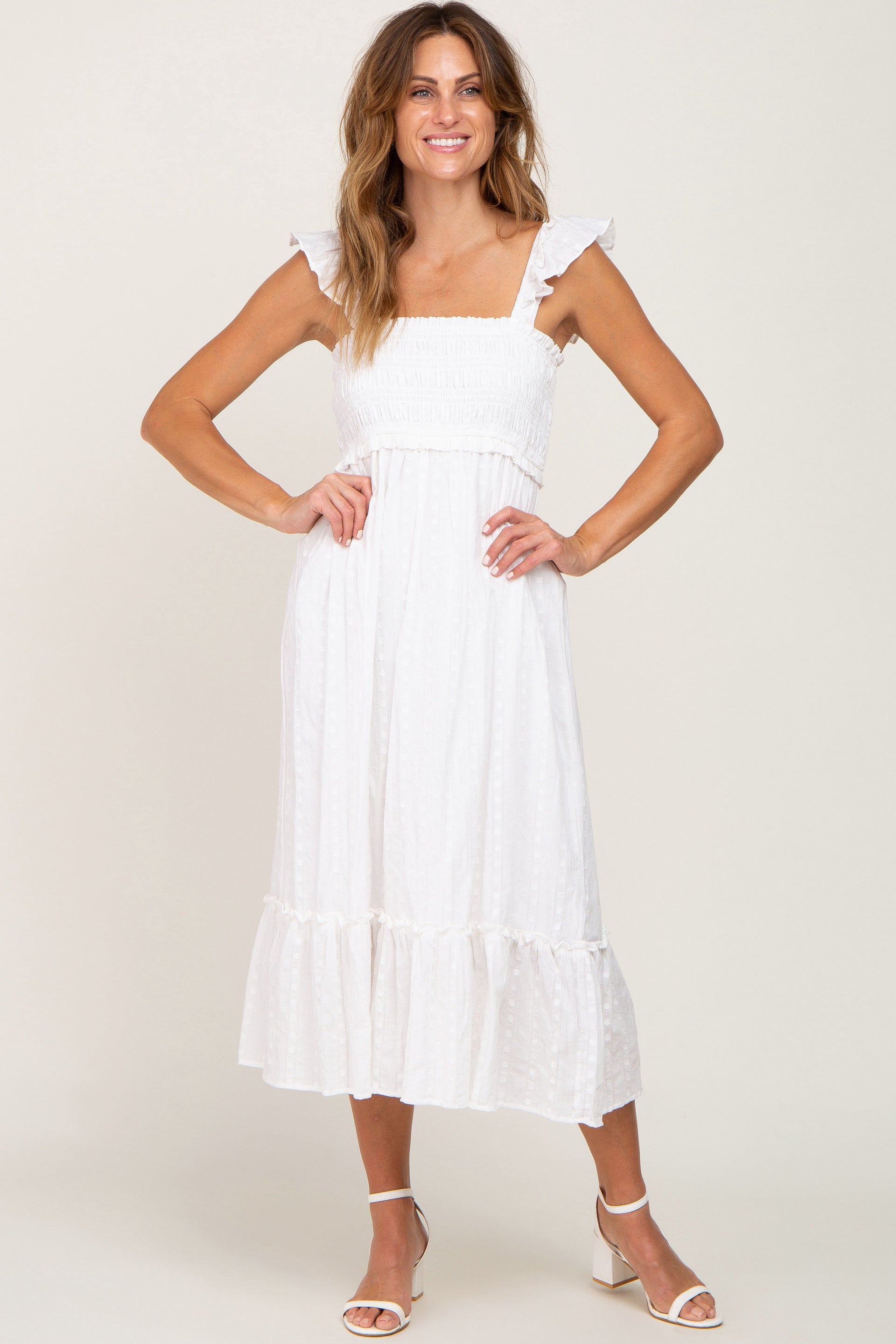 A woman wearing a white textured midi dress with a smocked bodice and flutter straps.