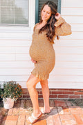 A pregnant woman wearing a yellow ditsy floral print maternity mini dress with long sleeves and a smocked bodice