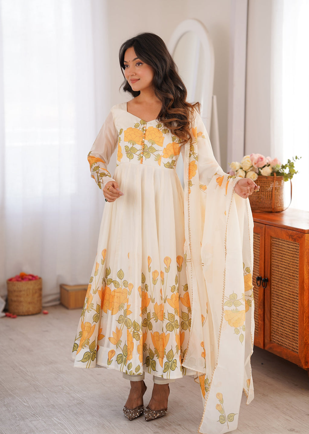 Woman wearing an offwhite organza silk Anarkali gown with floral print and potli button details