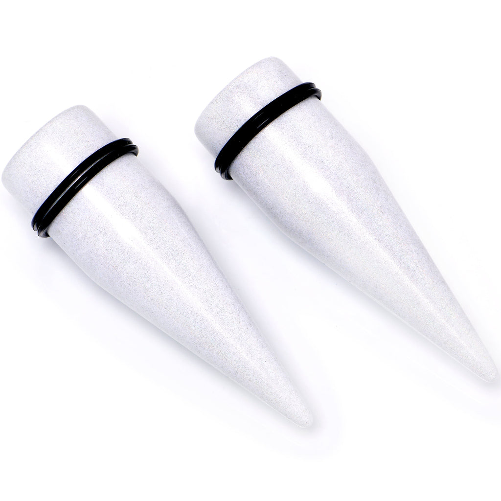 A pair of white shimmer acrylic straight ear tapers with black O-ring rubber bands for ear stretching.