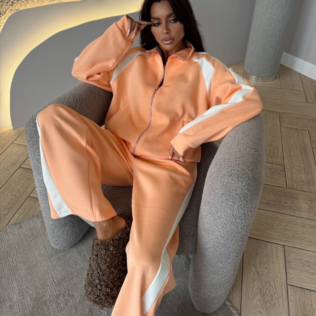 A woman wearing a two-piece matching tracksuit with a zip-up jacket and long pants.