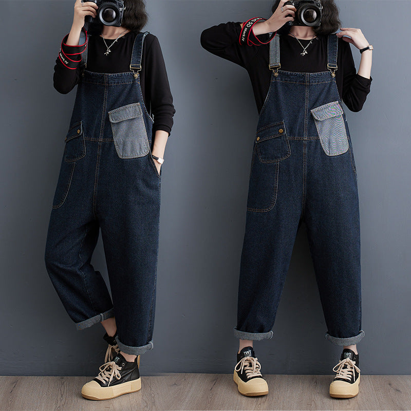 Woman wearing dark blue denim cropped overalls with a light blue chest pocket detail, black long-sleeve shirt, and sneakers, showcasing a relaxed fit and cuffed hems.
