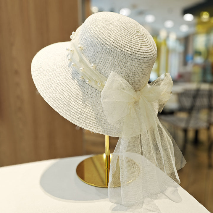 Women's straw beach sun hat featuring a delicate white bow and wide brim for UV protection.