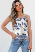 Woman wearing a sleeveless top with blue floral pattern and jeans against a white background
