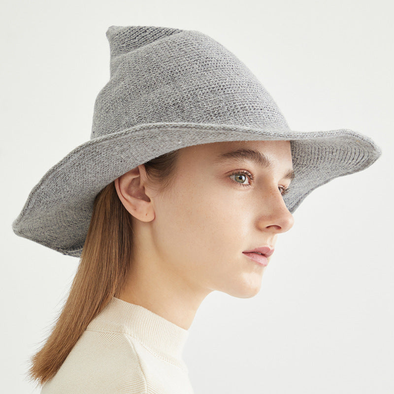 A woman wearing a grey wool high-top wizard hat with a wide brim, styled for a seasonal autumn look.
