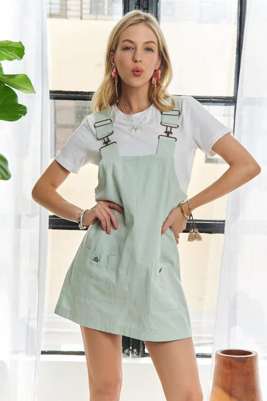 A chic square neck overall dress with wide adjustable straps, styled for a modern casual look.