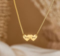 Gold interlocking heart pendant necklace featuring custom cursive name script.