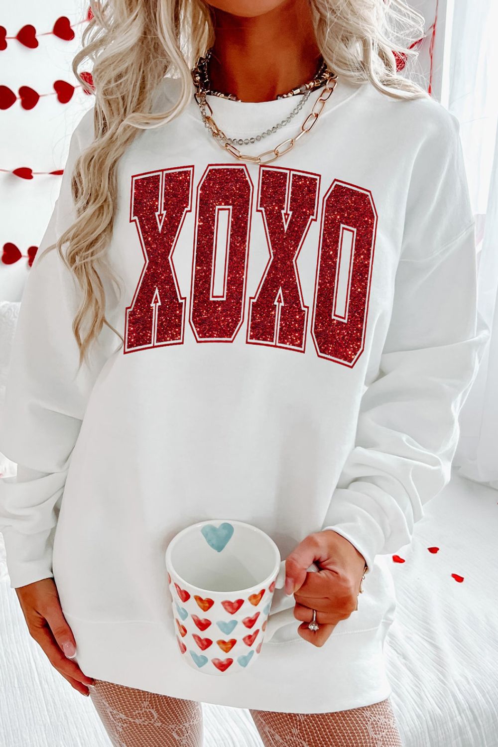 Women wearing a festive XOXO glitter sweatshirt for Valentine's Day in white or red