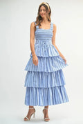 A woman wearing a light blue pinstripe midi dress with a smocked bodice and layered skirt.