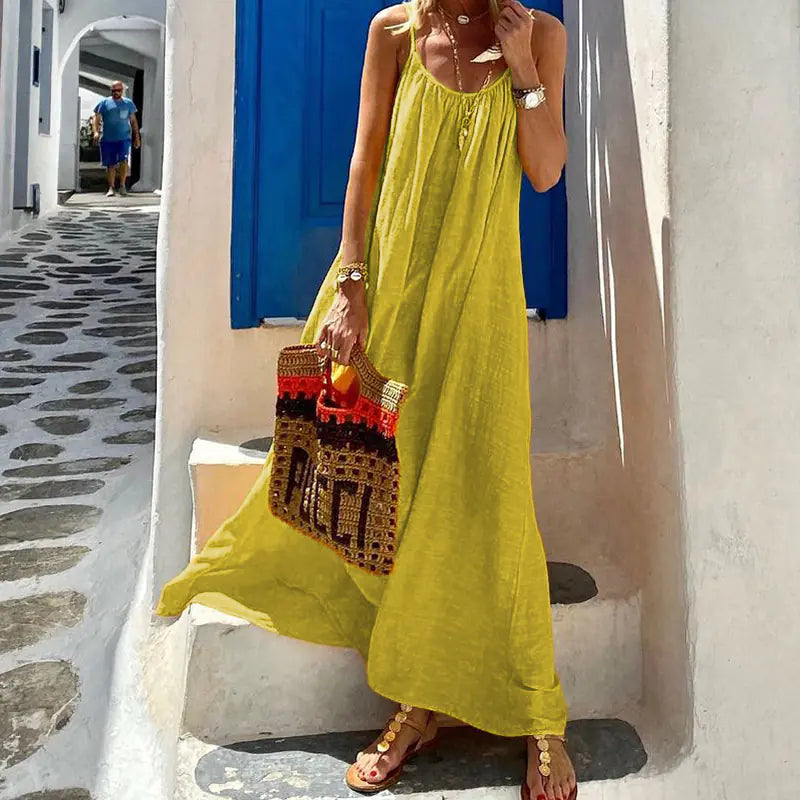 Model wearing a loose-fitting yellow maxi dress with a halter neckline in a sunny outdoor setting.