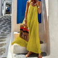 Model wearing a loose-fitting yellow maxi dress with a halter neckline in a sunny outdoor setting.