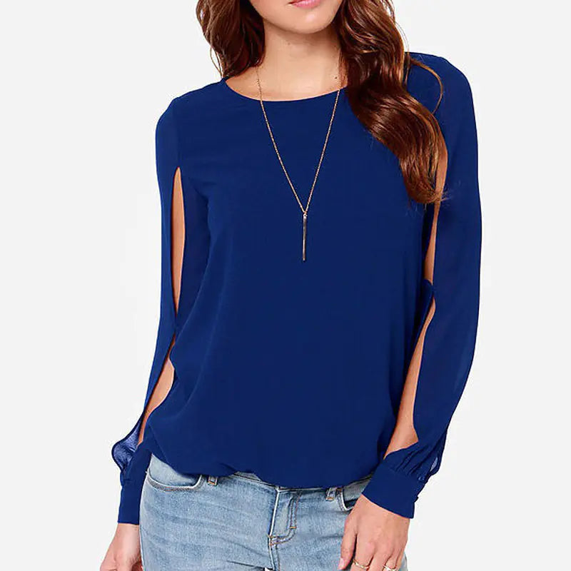 A woman wearing a royal blue long sleeve chiffon blouse with open sleeve detailing, paired with light wash denim jeans.