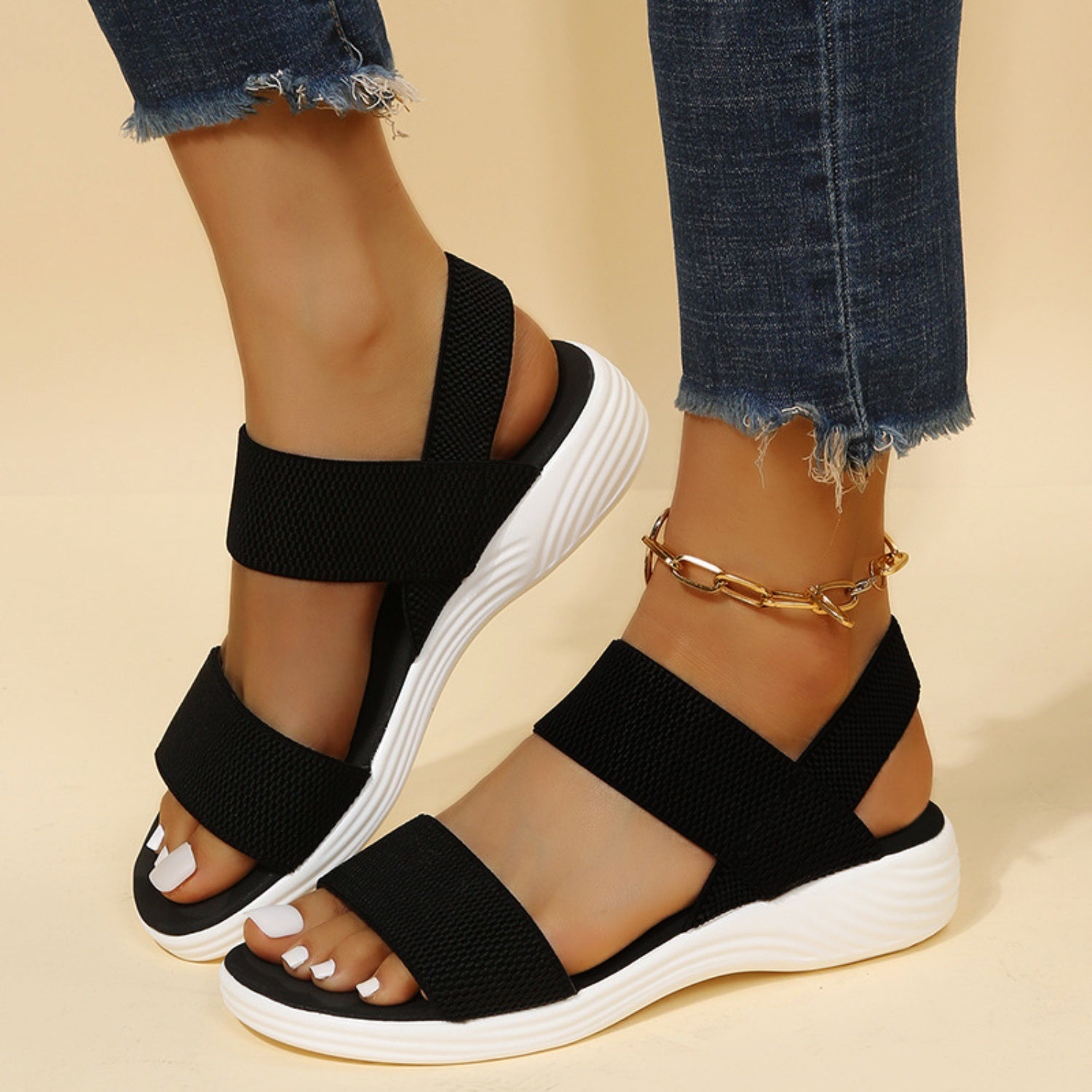 A pair of comfortable open-toe low heel sandals with elastic straps displayed on a neutral background.