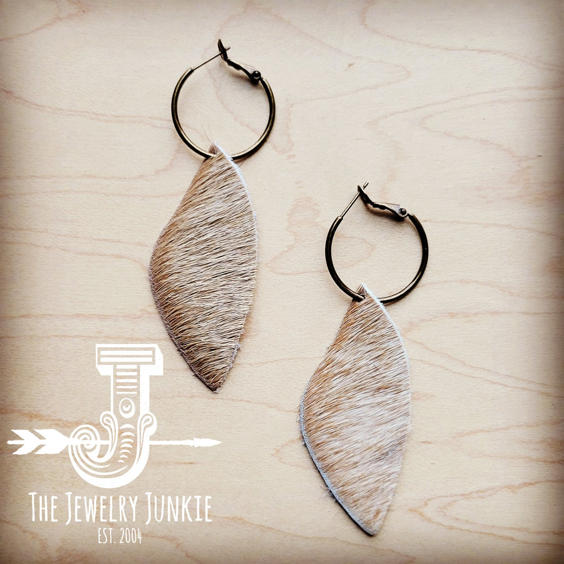 Antique gold hoop earrings featuring natural tan dark hair-on-hide leather dangles on a wooden background