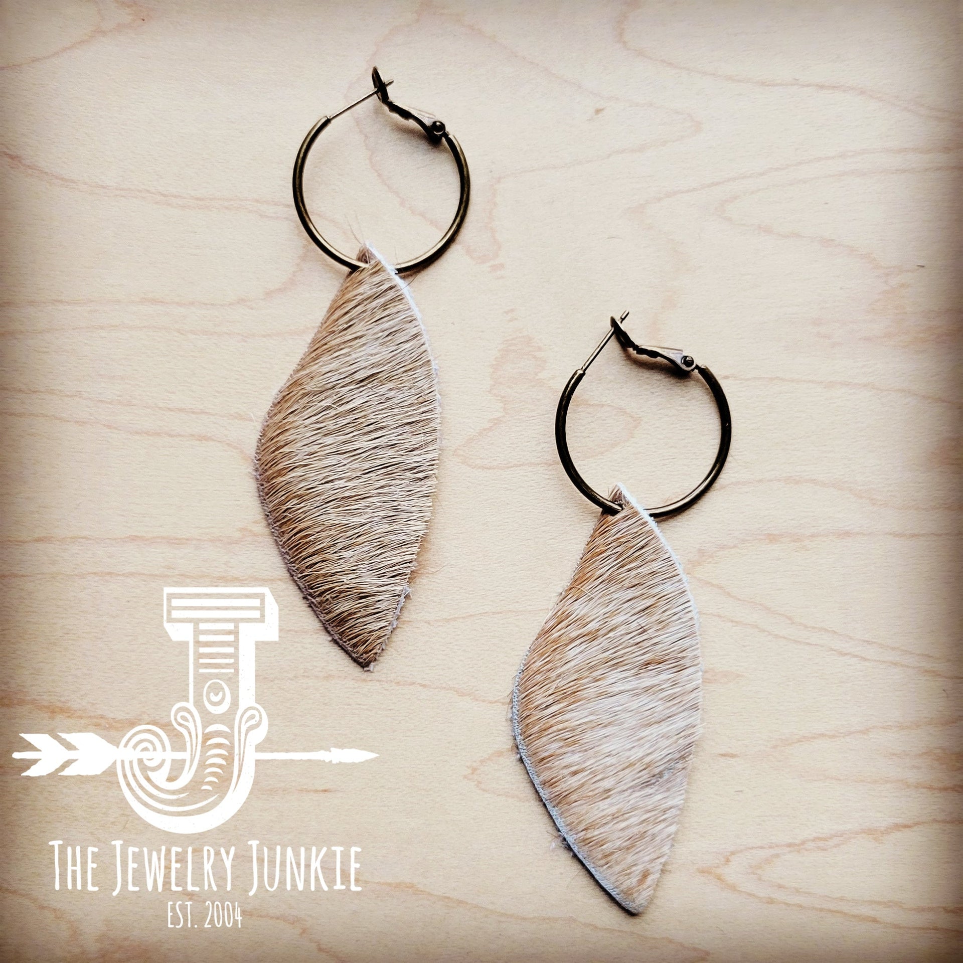 Antique gold hoop earrings featuring natural tan dark hair-on-hide leather dangles on a wooden background