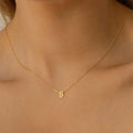 Minimalist gold dainty initial letter necklace worn by a woman