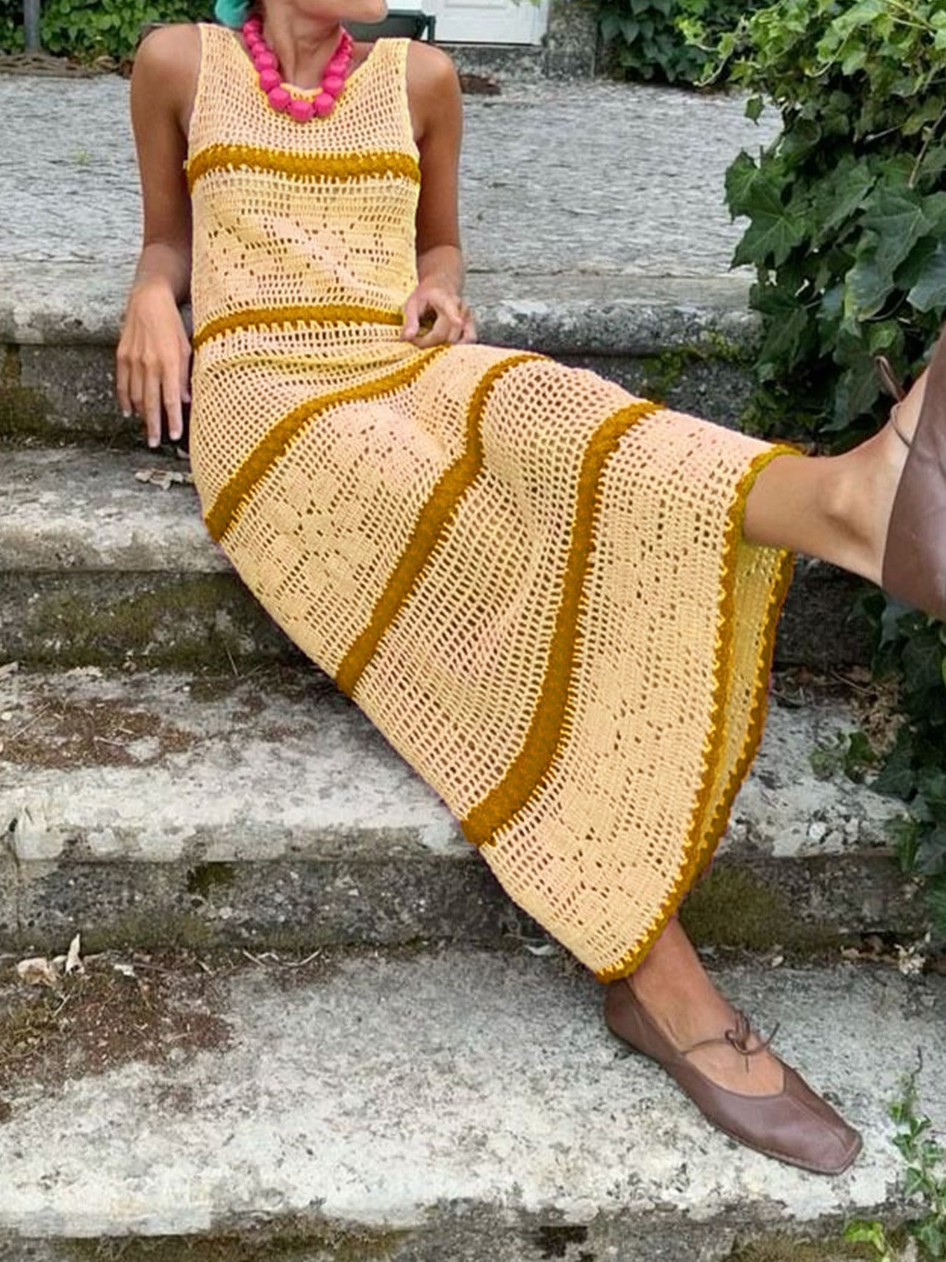 A sleeveless knitted hollow vest dress in contrast colors, styled as a long casual skirt.