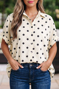 A woman wearing a polka dot tunic-length dolman shirt with rolled cuffs and a collar.
